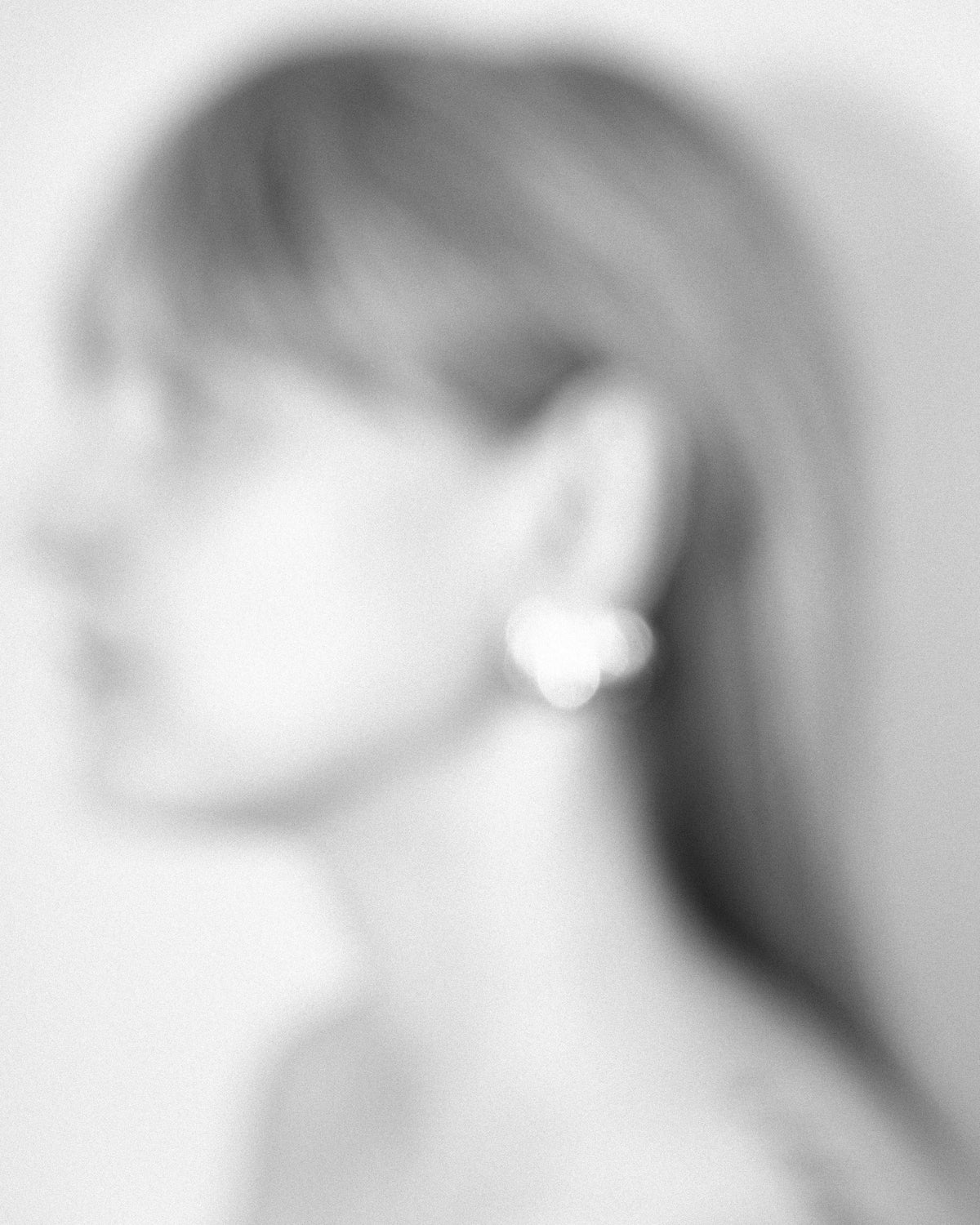 Blurred black and white image of a person wearing an earring
